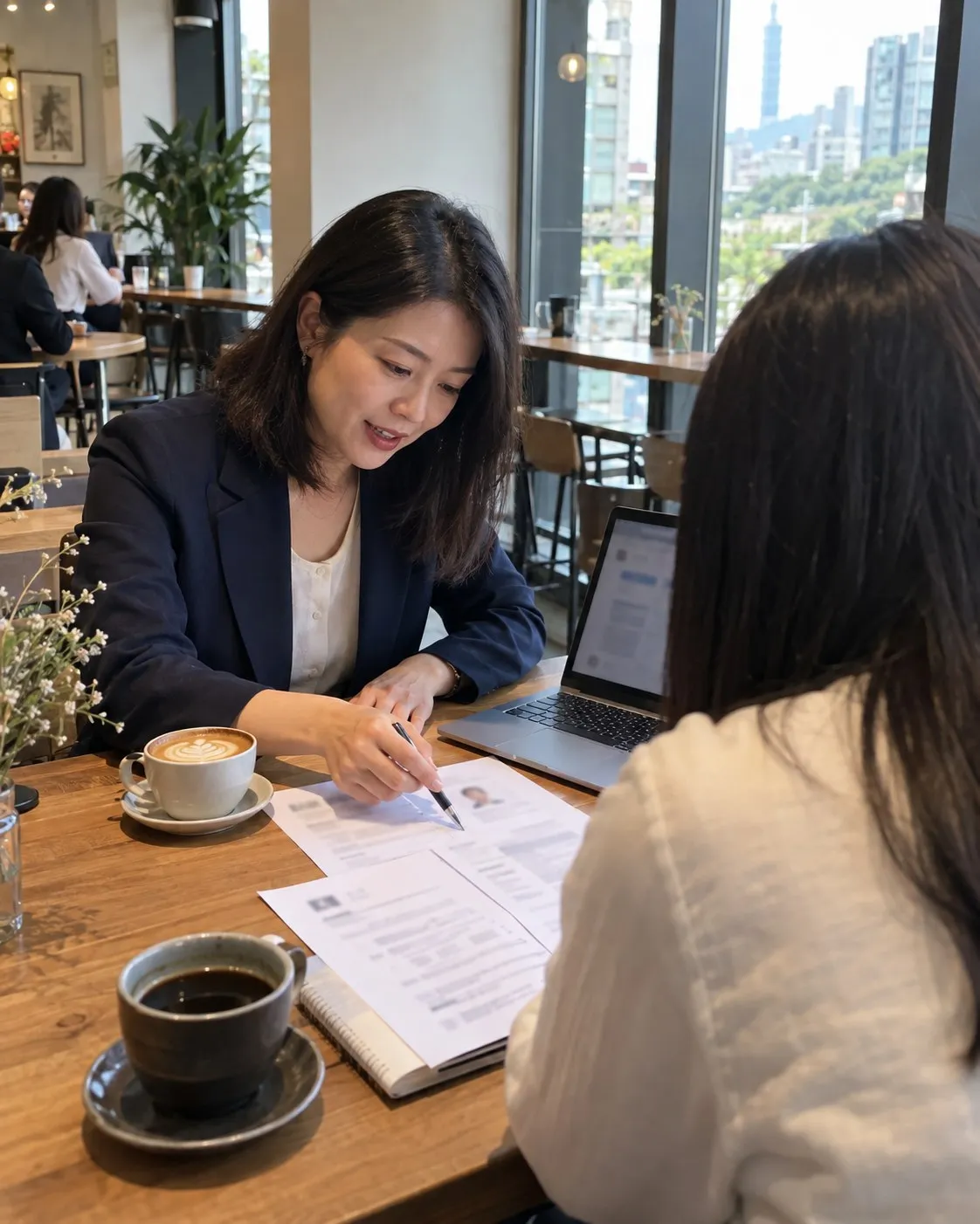 沈予安在咖啡店的木桌前，拿筆在印出來的履歷上寫建議，對面坐著學員，桌上有筆電和咖啡